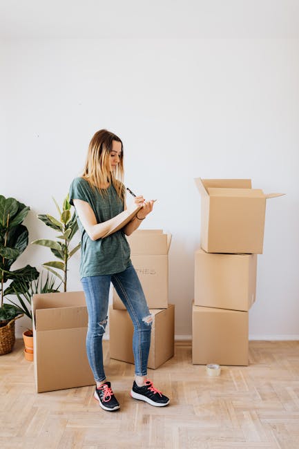 A young woman with shoulder-length blonde hair, dressed in a casual green t-shirt, ripped blue jeans, and black sneakers with pink laces, standing inside a residential space. She is holding a clipboar